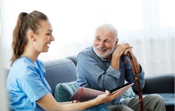 A senior man laughing with a female caregiver while he completed different memory care activities