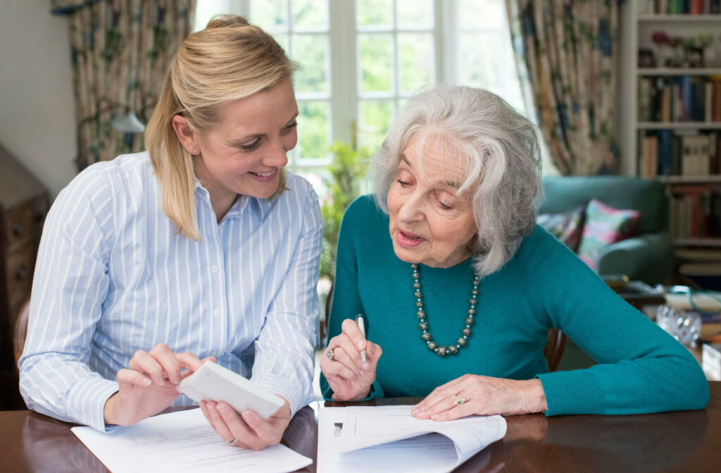 A young woman is helping senior mother on paperwork in selling her house.