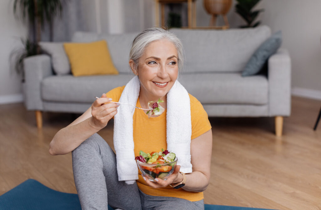 A senior woman in her workout clothes enjoying a bowl of salad.