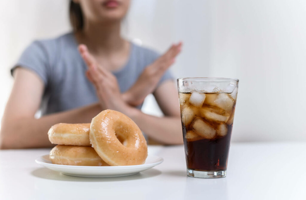 Young woman refusing unhealthy food like donuts or sugary soda.