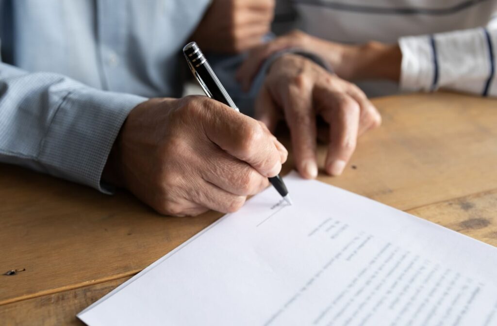 A close-up of a person signing a power of attorney document.