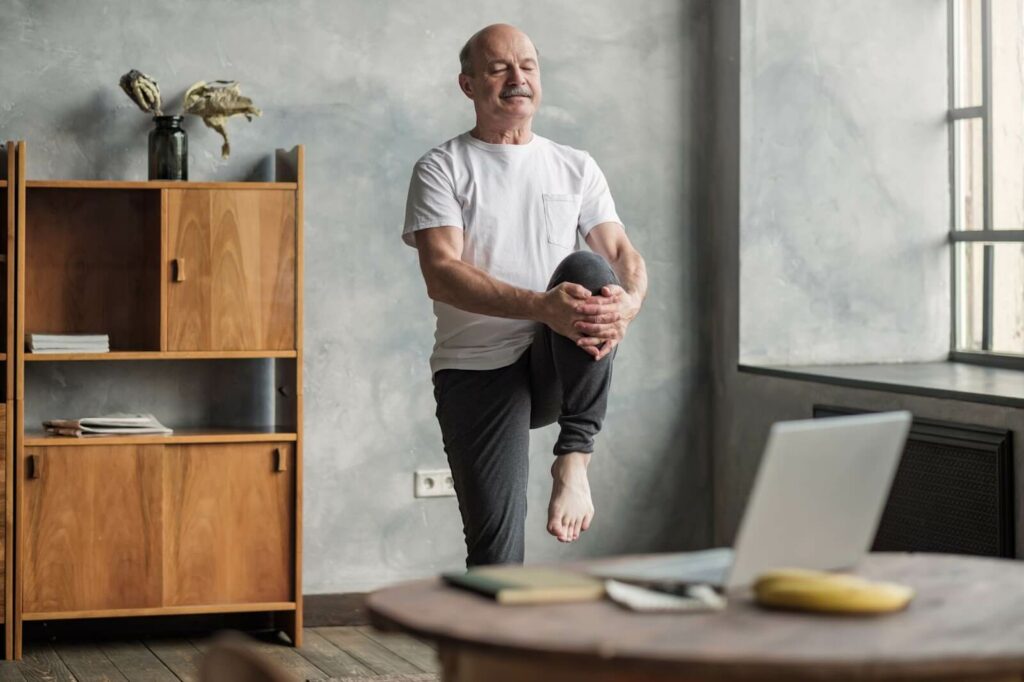 A senior man does yoga at home